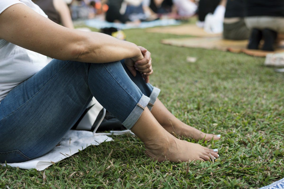 barefoot woman with jeans sitting on the grass