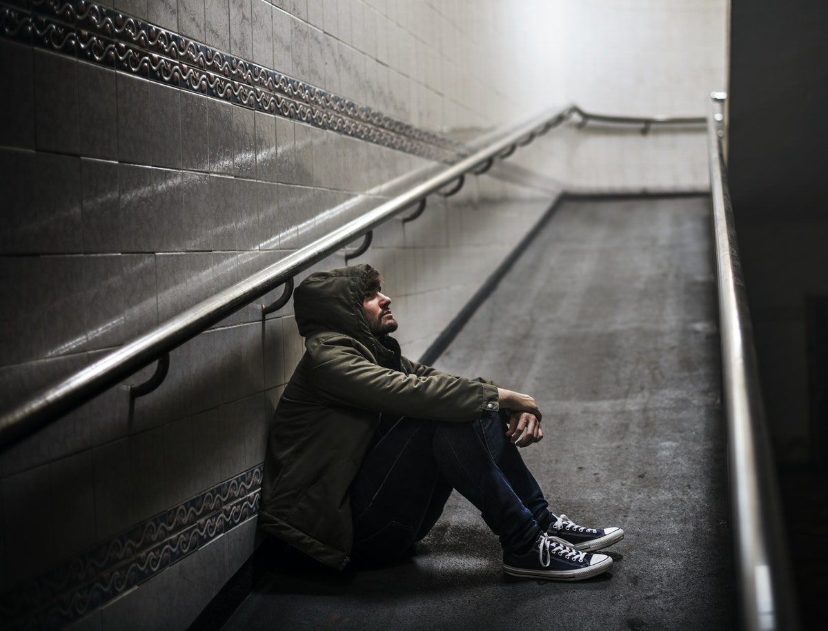 man with a hoodie sitting on the ground