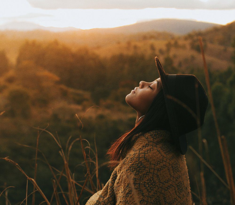 side view of woman looking up in a sunset