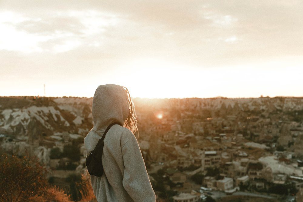 lady in a hoodie looking at a sunset