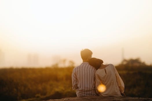 a couple in love sits and watches the sunset